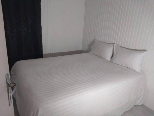 Bett mit weißer Bettwäsche und Kissen in einem Zimmer in der Unterkunft Peaceful home in Sevran