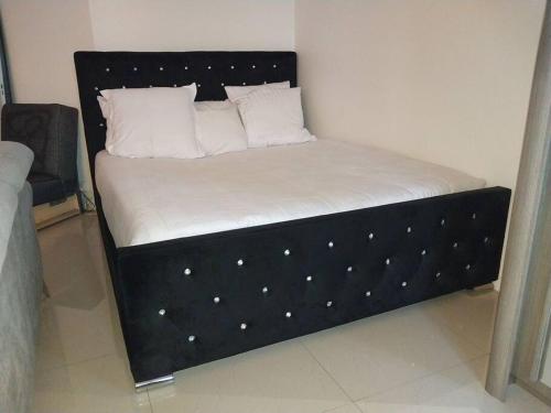 ein Bett mit schwarzem Gestell, weißen Laken und Kissen in der Unterkunft Peaceful home in Sevran