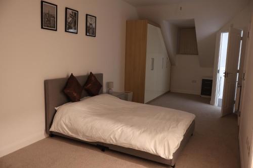 a bedroom with a large bed with white sheets at Modern house in City Centre with private parking and gated property in Birmingham