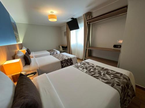a hotel room with two beds and a couch at Hotel El Tambo 2 in Lima