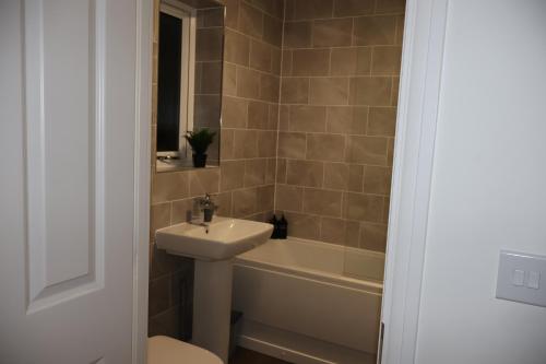 a bathroom with a sink and a tub and a toilet at Modern house in City Centre with private parking and gated property in Birmingham