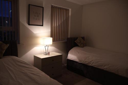 a bedroom with two beds and a lamp on a night stand at Modern house in City Centre with private parking and gated property in Birmingham