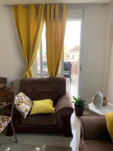 een woonkamer met een bank en gele gordijnen bij appartement face du mere in Tanger