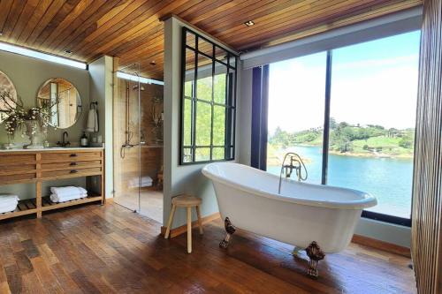 baño grande con bañera y ventana grande en Maremansa Lake House Guatapé, en Chiquinquirá