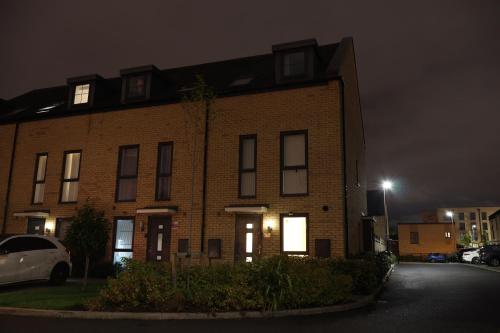 a brick house at night with a car parked in front at Modern house in City Centre with private parking and gated property in Birmingham