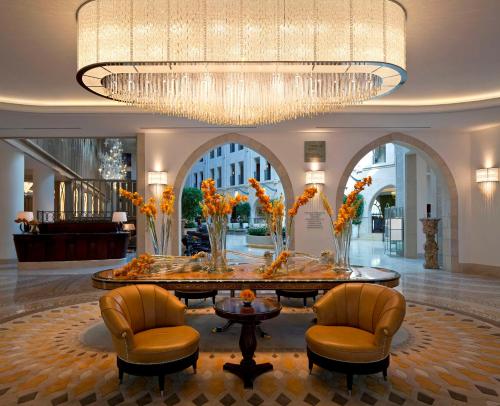 a lobby with a large chandelier and a table and chairs at Waldorf Astoria Jerusalem in Jerusalem