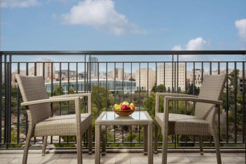 two chairs and a table with a bowl of fruit on a balcony at Waldorf Astoria Jerusalem in Jerusalem