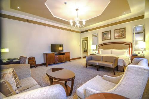 a hotel room with a bed and a couch and chairs at Waldorf Astoria Jerusalem in Jerusalem