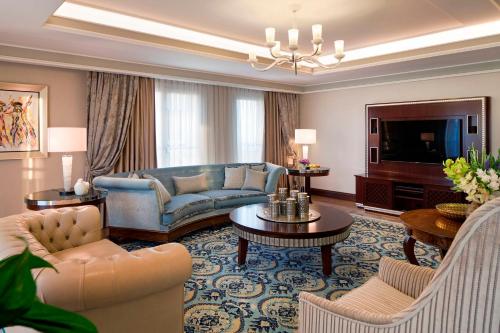 a living room with a blue couch and a tv at Waldorf Astoria Jerusalem in Jerusalem