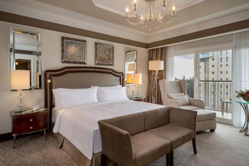 a bedroom with a bed and a chair and a chandelier at Waldorf Astoria Jerusalem in Jerusalem