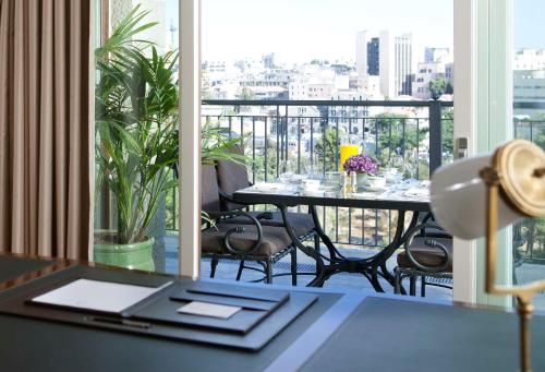 a table and chairs in a room with a balcony at Waldorf Astoria Jerusalem in Jerusalem