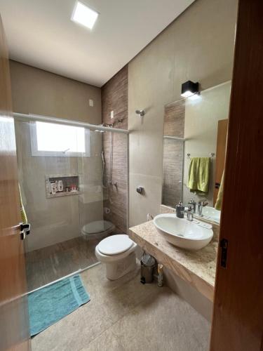 uma casa de banho com um lavatório, um WC e um chuveiro em Quartos privativos - Casa de alto padrão em Guaratinguetá