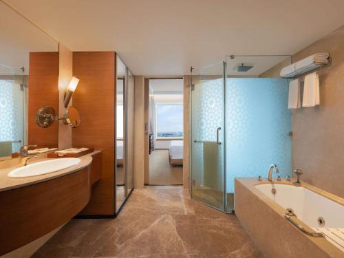a bathroom with a tub and a sink and a shower at Radisson Blu Hotel Ranchi in Rānchī