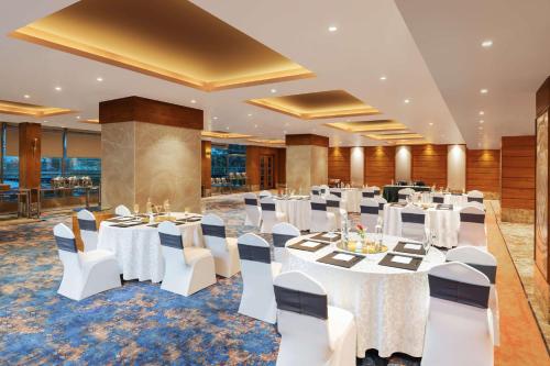 a banquet hall with white tables and white chairs at Radisson Blu Hotel Ranchi in Rānchī