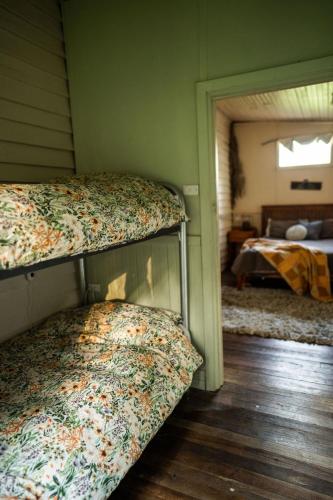 two bunk beds in a room with a bedroom at Cosy Farmstay: Green Cabin at Whispering Woods in Beedelup