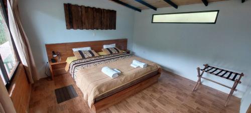 1 dormitorio con cama con almohadas y ventana en Mindo Loma bird lodge, en Mindo