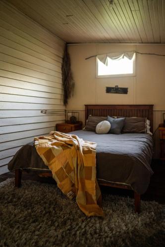 a bedroom with a bed in a room with a window at Cosy Farmstay: Green Cabin at Whispering Woods in Beedelup