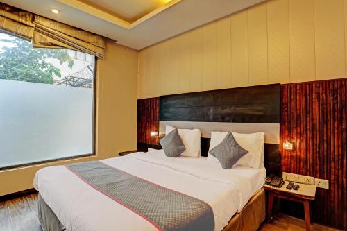 een slaapkamer met een groot bed en een groot raam bij Super Townhouse 1242 Tipsyy Inn 16 in Gurgaon