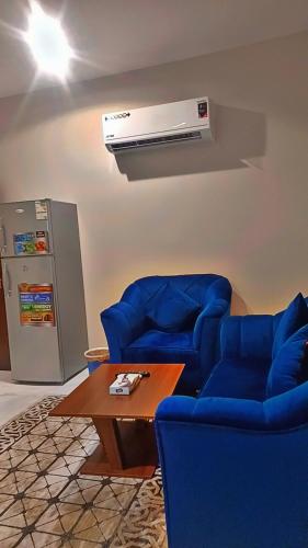 a living room with two blue chairs and a heater at جوهرة العزيزية للشقق المفروشة in Medina