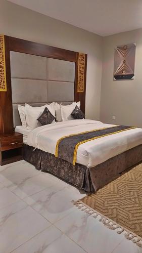 a bedroom with a large bed with a wooden headboard at جوهرة العزيزية للشقق المفروشة in Medina