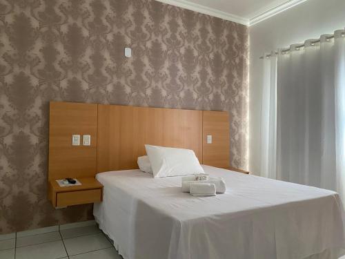 a bedroom with a large bed with a white blanket at FLORENÇA PALACE HOTEL in Lucas do Rio Verde