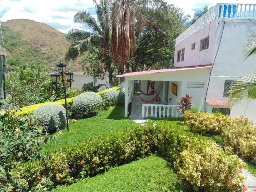 uma pequena casa branca com um jardim verde com arbustos em Hotel Bella Vista Isla Del Sol em Prado