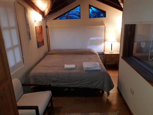 a small bedroom with a bed and two windows at Cabaña entre Arboles in San Carlos de Bariloche