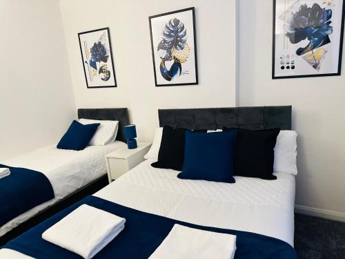 Lovely 4 Bedroom House with 2 Bathroom, Garden and Private Parking في Thornton Heath: سريرين في غرفة باللون الأزرق والأبيض