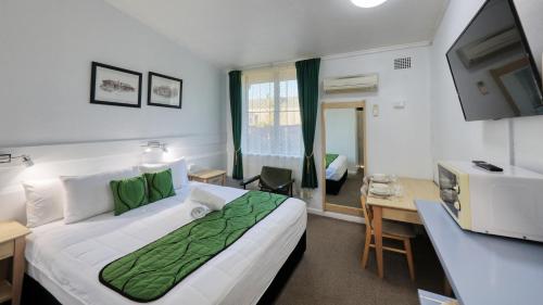 Habitación de hotel con cama grande y escritorio. en CBD GI Motel, en Glen Innes