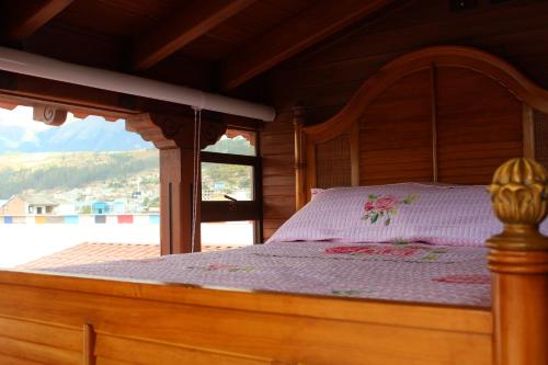 Cama de madera en habitación con ventana en Chaska Hotel, en Otavalo