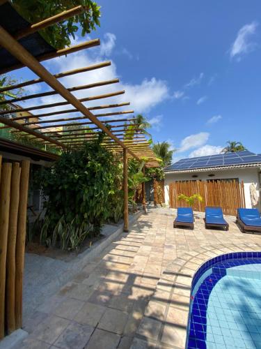 a wooden pergola over a swimming pool with blue chairs at Pousada Barbara in Pipa