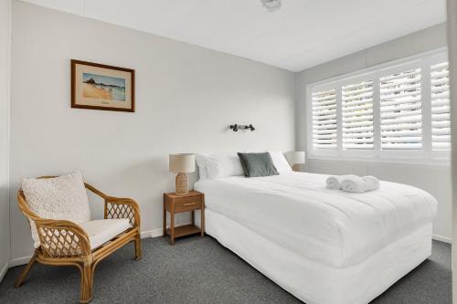 um quarto branco com uma cama e uma cadeira em White Dolphin, Unit 7 em Gold Coast