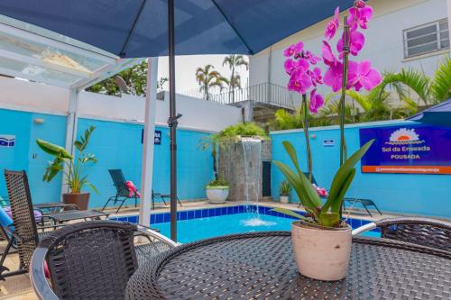 una mesa de patio con una planta en una olla junto a una piscina en Pousada Sol da Enseada Guarujá, en Guarujá