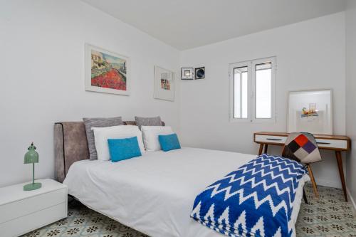 a bedroom with a large white bed with blue pillows at Sea House in São Vicente