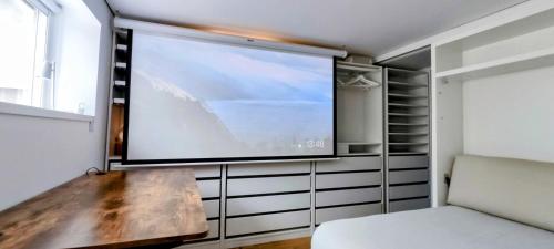 a large flat screen tv in a room with a bench at IH Apartments & Studios in Espinho
