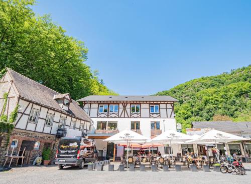 a large building with tables and umbrellas in front of it at Landhotel Ringelsteiner Mühle in Moselkern