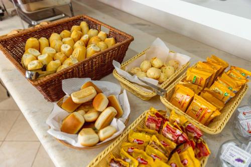 a table topped with baskets of bread and snacks at Pousada Sol da Enseada Guarujá Inn - Piscina Aquecida in Guarujá