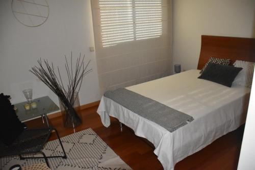 a bedroom with a bed and a chair and a window at Casa de praia familiar 4 quartos e jardim in Esposende
