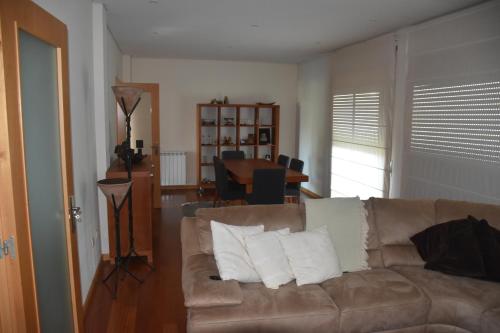 a living room with a brown couch with pillows at Casa de praia familiar 4 quartos e jardim in Esposende