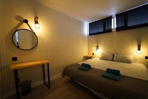 een slaapkamer met een bed met een spiegel en een tafel bij Tropical Views - Paya del Inglés in Maspalomas