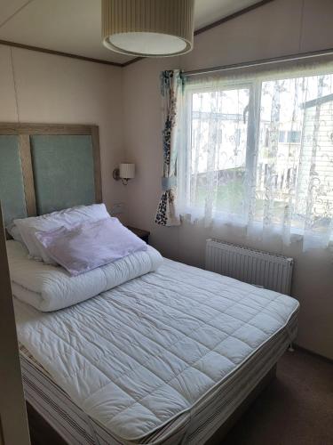 a bedroom with a white bed with a window at Your Retreat Too in Camber