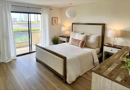 a bedroom with a large bed and a balcony at Beachfront Paradise in Port Hueneme