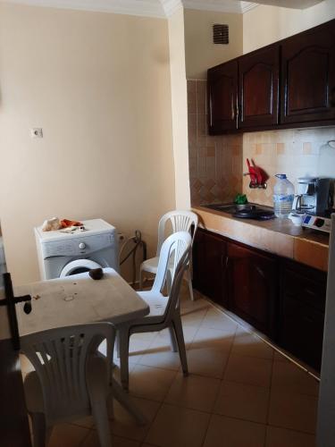 - une cuisine avec deux chaises, une table et une cuisinière dans l'établissement Elhouda 56, à Agadir