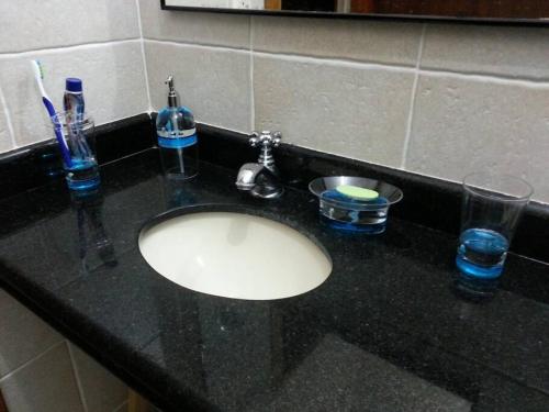 a bathroom counter with a sink and glasses on it at Casa para Temporada em Cananéia in Cananéia