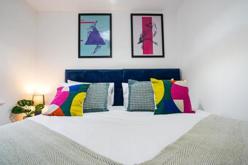1 dormitorio con cama blanca y almohadas coloridas en Stunning Harvest Way House, en Witney