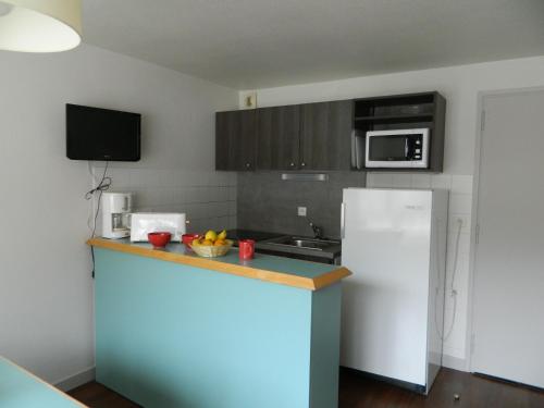 a kitchen with a white refrigerator and a microwave at VVF Val-Cenis Haute-Maurienne in Lanslevillard