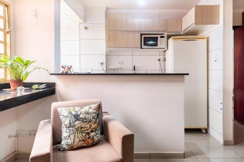 a kitchen with a refrigerator and a chair in a room at Apartamento de um quarto, próximo ao Estadual. in Bauru