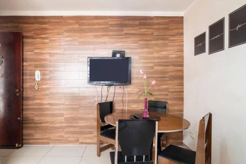 uma sala de jantar com uma mesa e uma televisão na parede em Apartamento de um quarto, próximo ao Estadual. em Bauru