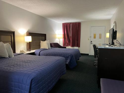 ein Hotelzimmer mit 2 Betten und einem TV in der Unterkunft Garden Inn & Suites in Metter