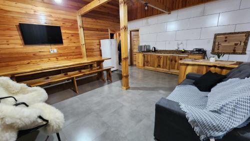 sala de estar con sofá y TV y cocina en Recanto Pôr do Sol, en Urubici